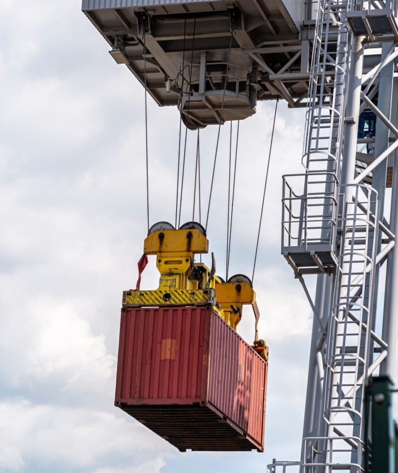 A container gantry crane on a rail loads the container into a barge standing on the banks of the river Rhine in Germany.